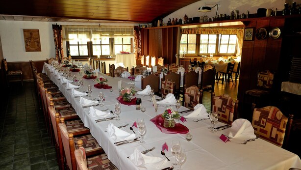 A long dining table set with white tablecloths, red napkins, and floral centerpieces. - Zum Mühlehannes (Sankt Ingbert)