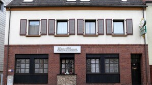 A building with a sign reading "König Rilse". It has a tiled roof, multiple windows with shutters, and a brick facade. - Zum Mühlehannes (Sankt Ingbert)