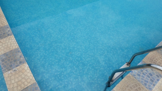A clear view of a swimming pool with a tiled edge and a metal pool ladder. - Indices Hotel and Garden (Abeokuta)