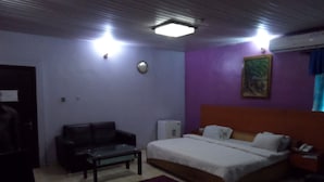 A hotel room with a bed, a sofa, a small table, and a desk. - Indices Hotel and Garden (Abeokuta)