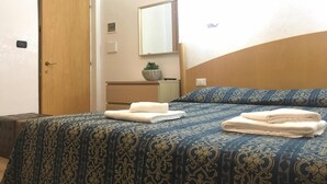 A bedroom with a bed, a wooden door, a small bedside table with a plant, and a mirror on the wall. - Tawhid Accomodation (Rome)
