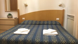 A hotel room with a bed, a nightstand, a mirror, and a potted plant. - Tawhid Accomodation (Rome)