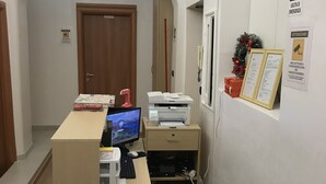 A reception desk with a computer, printer, and a small seating area. - Tawhid Accomodation (Rome)