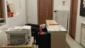 A hallway with a desk, printer, and a map on the table. There are two doors, one labeled "PRIVATE" and another with a sign. - Tawhid Accomodation (Rome)