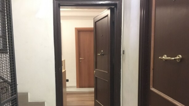 A hallway with a wooden door, a welcome mat, and a staircase. - Tawhid Accomodation (Rome)