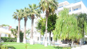Une cour intérieure agrémentée de palmiers, avec des espaces de détente en plein air et un espace piscine.