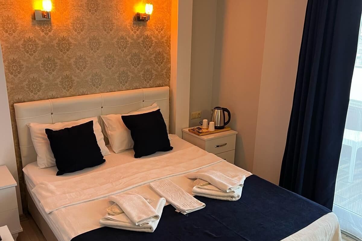 Une chambre d’hôtel avec un lit, deux lampes de chevet, une table de chevet et une fenêtre avec des rideaux.