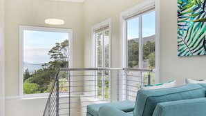 A balcony with a view of a coastal landscape, a white railing, and a teal sofa. - Mount Bay (Cape Town)