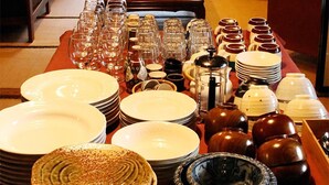 Un comedor con una mesa dispuesta para una comida, que presenta diversos platos y copas.
