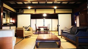 Un salón japonés tradicional con suelo de tatami, una mesa baja de madera y un sofá.