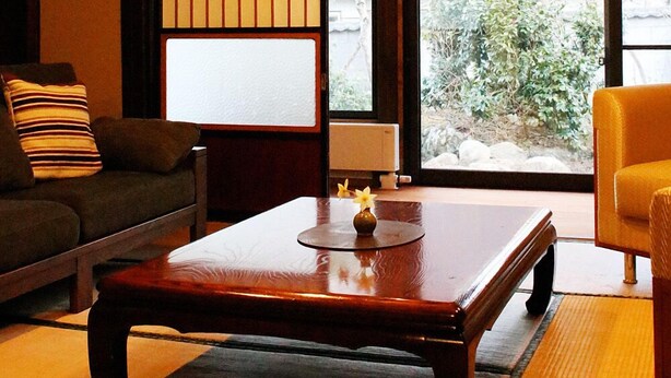 Una habitación tradicional japonesa con suelo de tatami, una mesa de madera baja, un sofá y un divisor corredizo shoji.