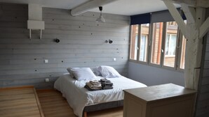 Een slaapkamer met een bed, een houten vloer, een raam en een klein bureau.