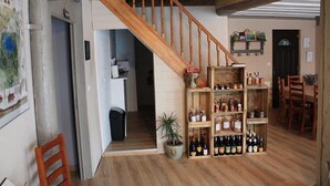 Een houten trap die leidt naar een eetgedeelte met een wijnrek en stoelen.