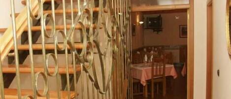 A staircase with ornate metal railings leading to a dining area with a table set for two.