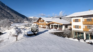A snow-covered mountain resort with wooden buildings, a clear sky, and a snow-covered landscape. - Hotel Garni Hanauerlehen (Schoenau am Koenigssee)