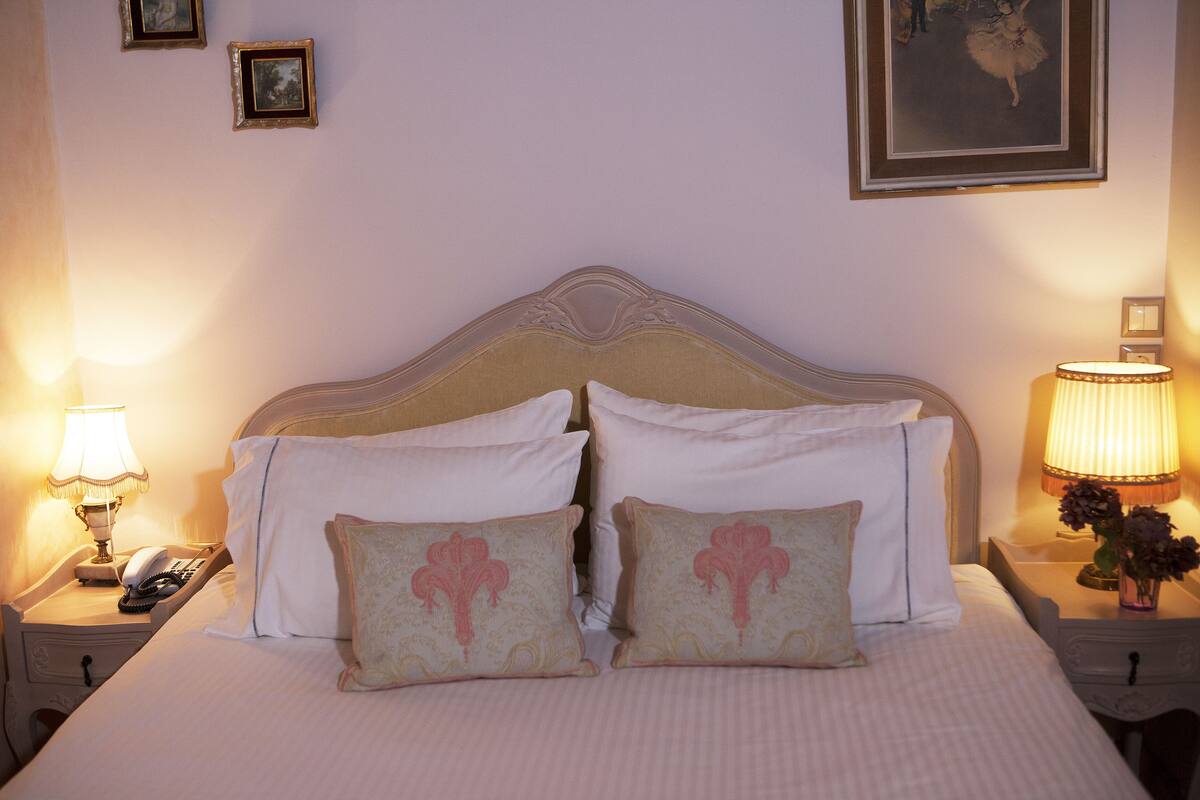 A neatly made bed with a headboard, two bedside tables with lamps, and a framed picture on the wall.