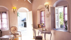 Una habitación con una cama, dos sillas, una mesa, una lámpara y una ventana con vistas a zonas verdes.