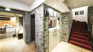 Un área de recepción con pared de piedra y una escalera que sube a un piso superior.