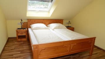 A bedroom with a wooden bed, two bedside tables, a skylight, and a wooden floor.