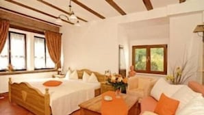 A room with a bed, a sofa, a coffee table, and a window with curtains. - Zum Alten Wasserrad - L Antica Ruota (Annweiler am Trifels)