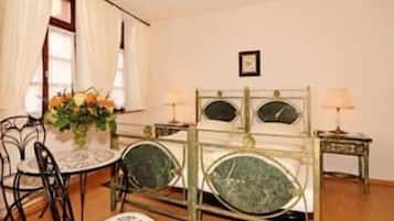 A room with a bed, a chair, a small table, and a lamp.