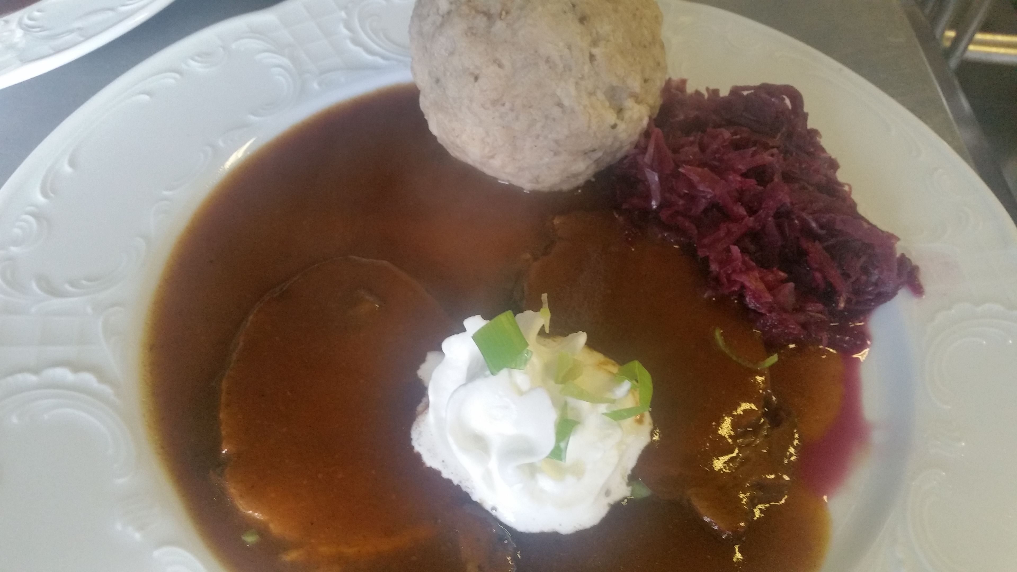 Une assiette contenant une boulette, de la choucroute et une cuillère de crème aigre.