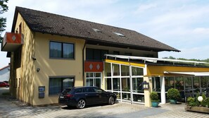 Ein zweigeschossiges Gebäude mit einem geparkten Auto davor.