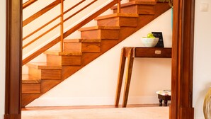 Una escalera de madera con una pared blanca y una pequeña mesa con un cuenco de fruta.