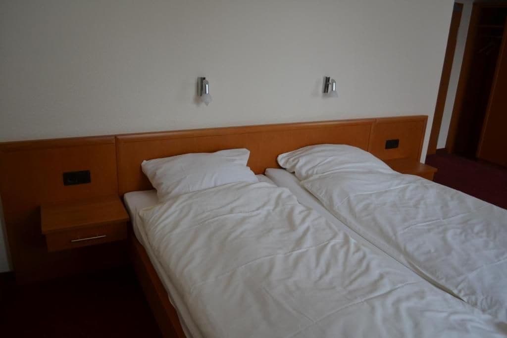 A single bed with a wooden headboard and two bedside tables, one with a drawer.