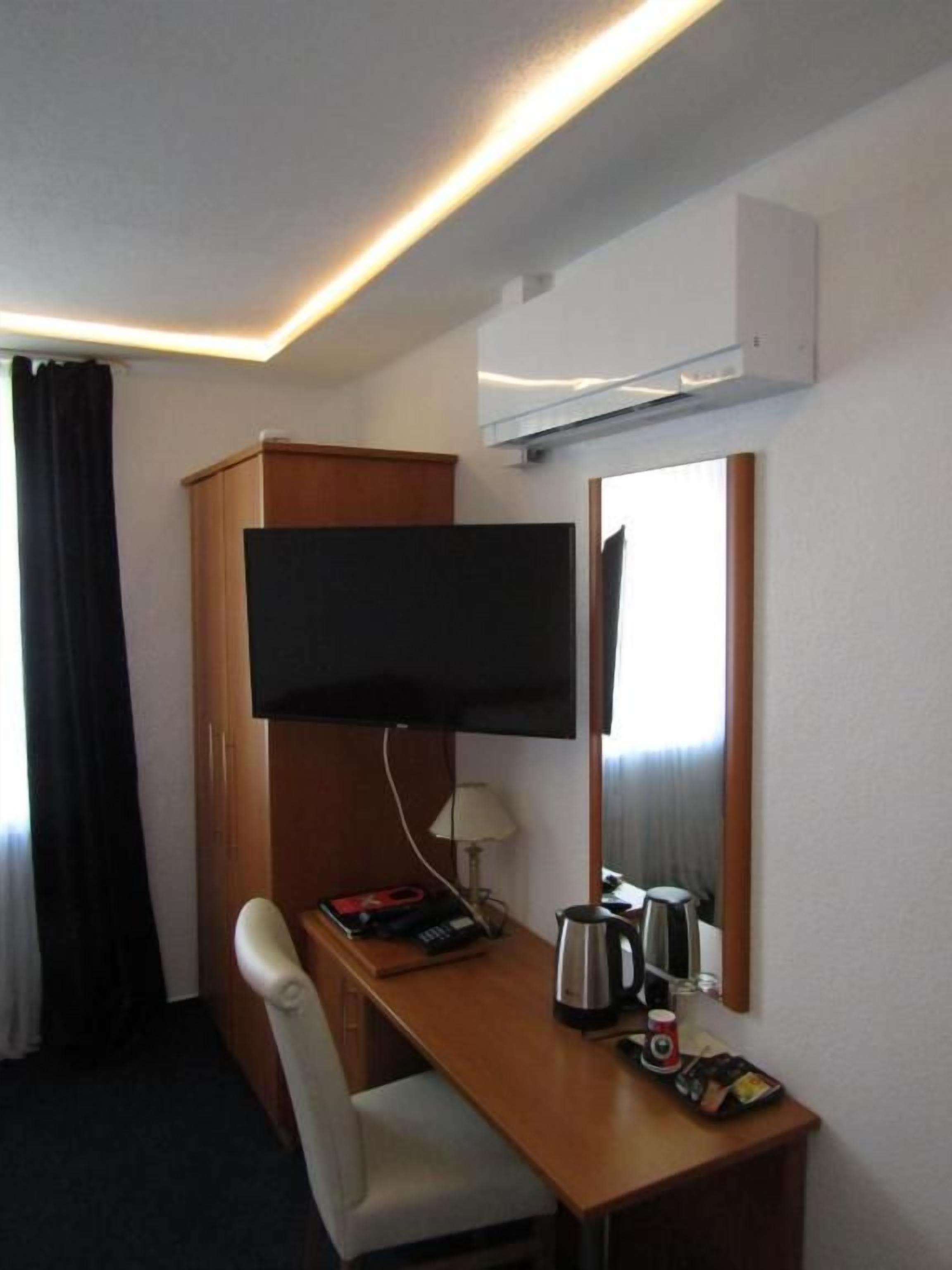 Une chambre d’hôtel équipée d’un bureau, d’une chaise, d’un téléviseur à écran plat et d’un miroir.