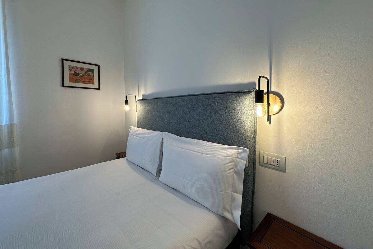 A neatly made bed with white linens in a hotel room.