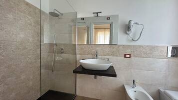 A modern bathroom with a glass-enclosed shower, a white sink, and a bidet.