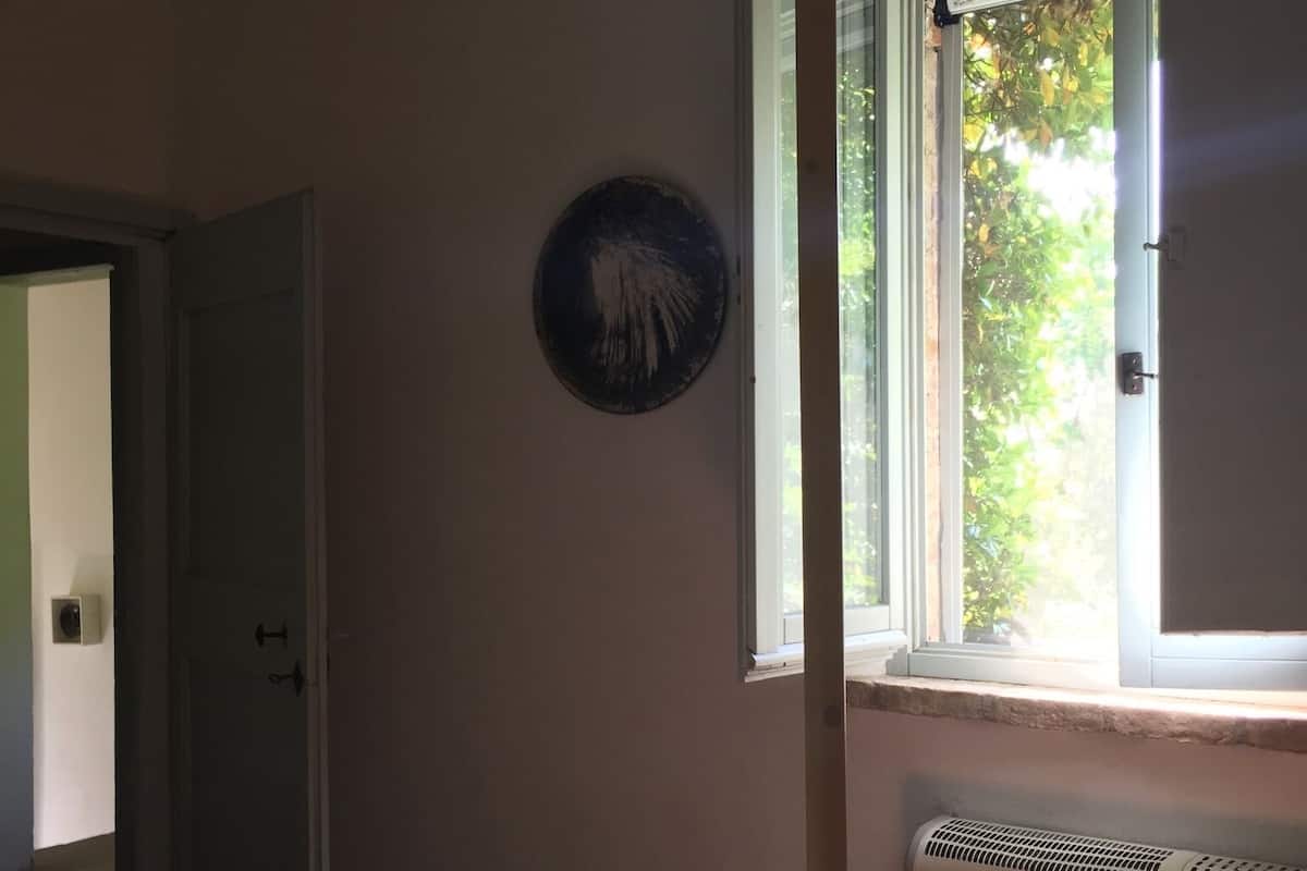 Un dormitorio con cama, radiador, ventana y puerta.