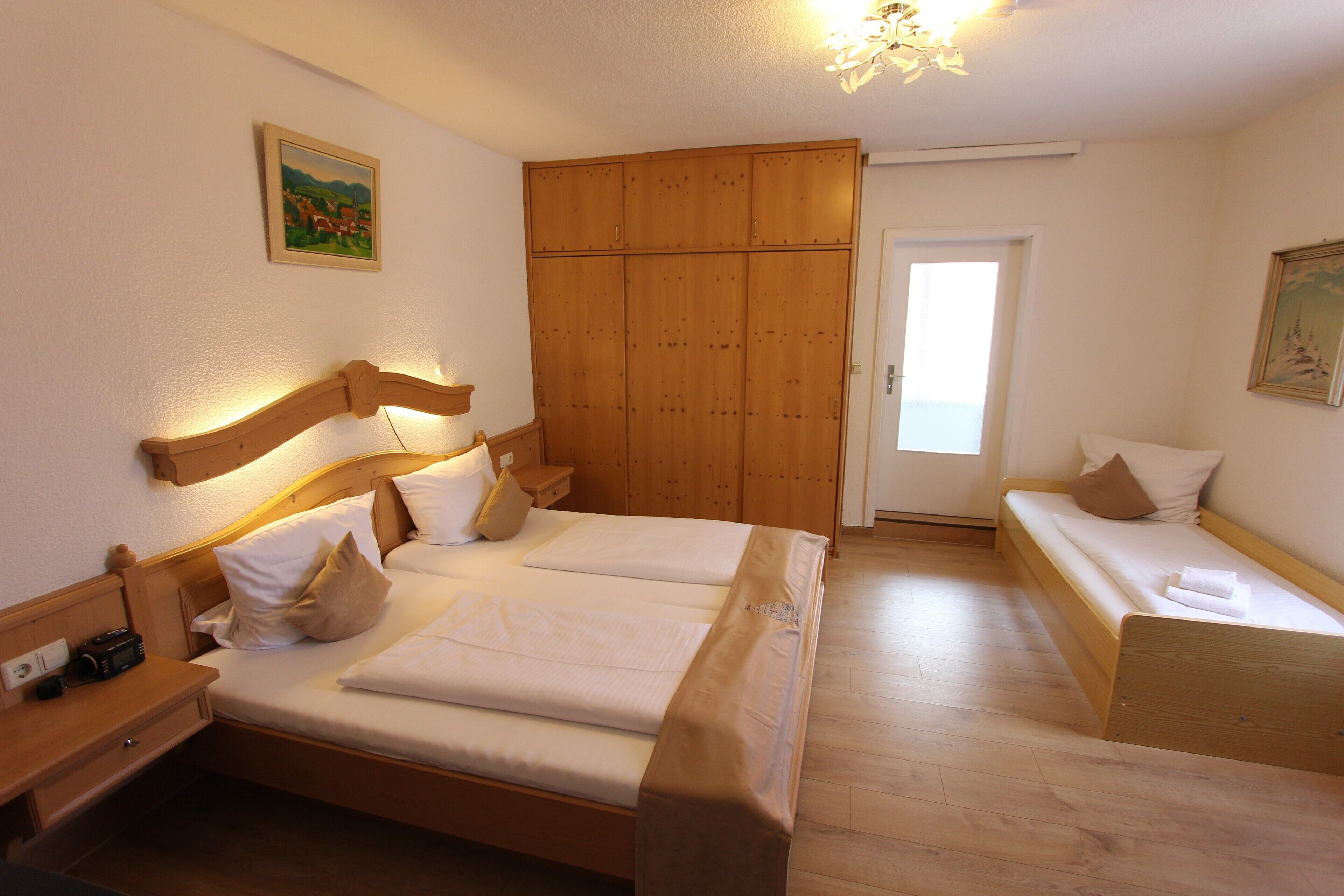 Un dormitorio con cama de madera, armario de madera, mesita de noche y un banco.