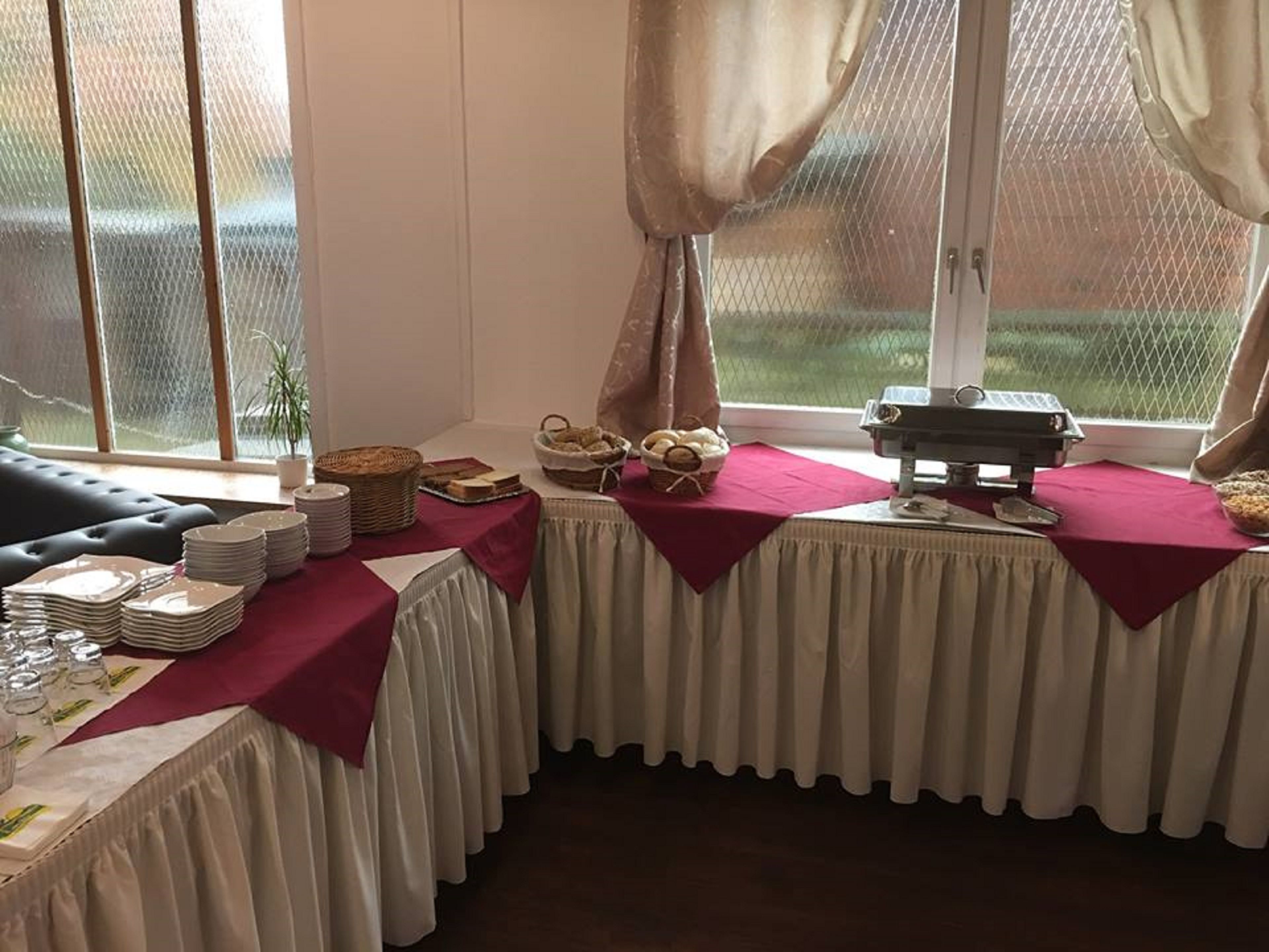 Een eetruimte met gedekte tafels, inclusief broodmanden, borden en glazen.