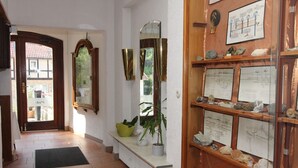 A hallway with a bench, a mirror, and a display of rocks and minerals. - Hotel Glück Auf (Bad Grund)