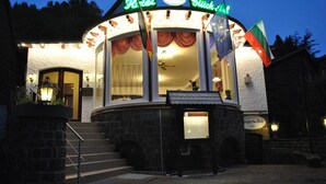 A hotel with a curved facade, a sign reading "Hotel Glück," and multiple flags. - Hotel Glück Auf (Bad Grund)