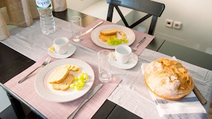 Uma mesa de café da manhã com torradas, uvas e um pão, uma garrafa de água e uma xícara.