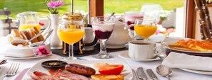 Une table dressée pour le petit-déjeuner, avec différents plats, boissons et ustensiles.