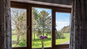A window with a view of a green landscape and a tree. - Langdon Farm Guest House (Kilgetty)
