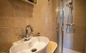Une salle de bain avec un lavabo, une douche et une porte en verre.