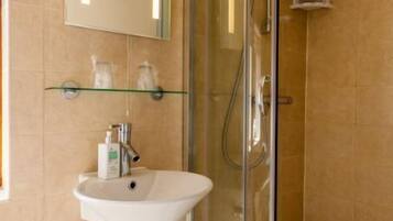 A bathroom with a glass-enclosed shower, a white sink, and a mirror above it.