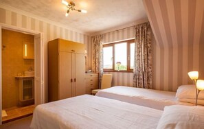 Une chambre d’hôtel avec deux lits, une armoire, un bureau et une fenêtre avec des rideaux.
