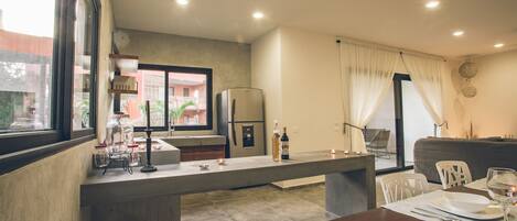 A modern kitchen with a built-in island, a dining area with a table set for two, and a view of the outside through large windows.