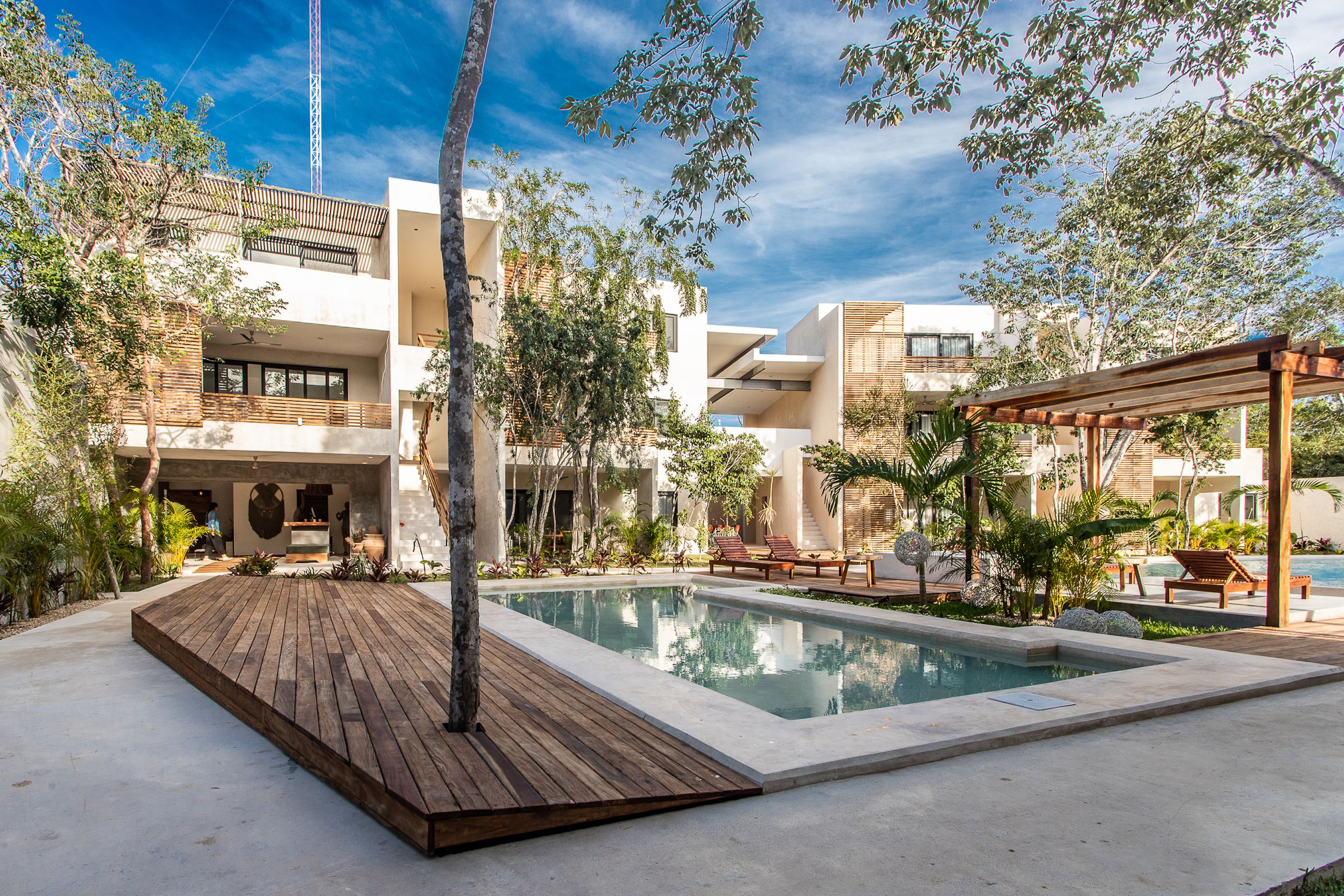 Een zwembadgedeelte in moderne stijl met een houten terras, ligbedden en een pergola.