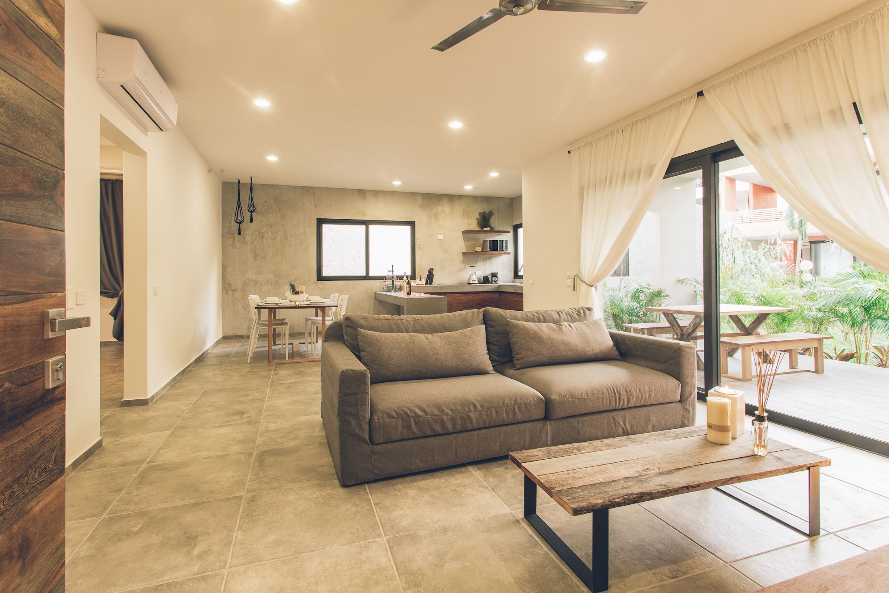 A modern living room with a sofa, a coffee table, and a dining area with a table and chairs.