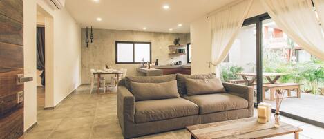 A modern living room with a sofa, a coffee table, and a dining area with a table and chairs.