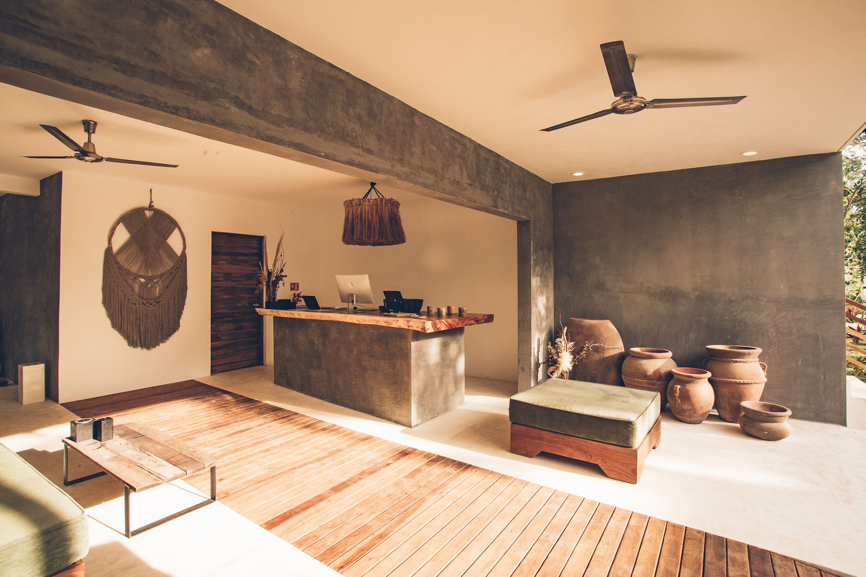 A modern interior with a wooden floor, a central island with a wooden countertop, a hanging light fixture, and a ceiling fan.