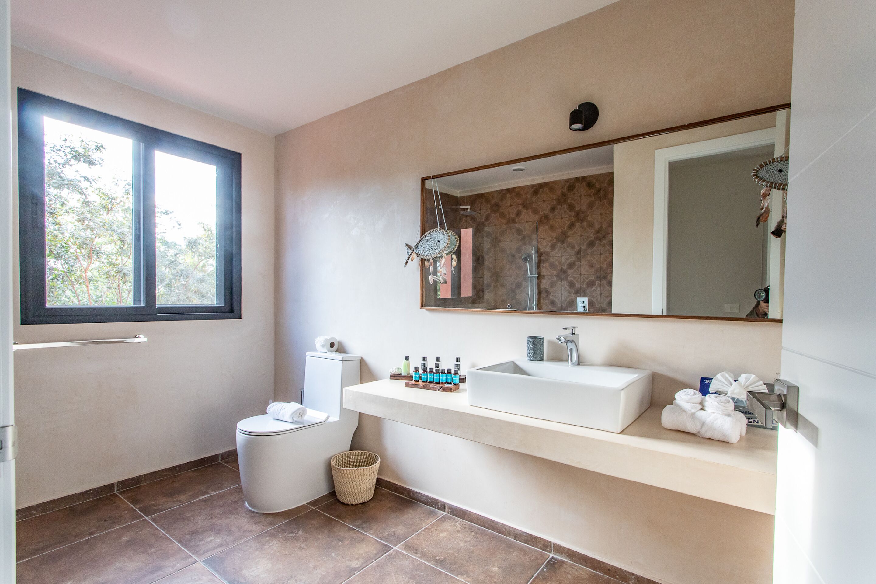 Ein modernes Badezimmer mit einem großen Fenster, einem weißen Waschbecken und einem Spiegel darüber.