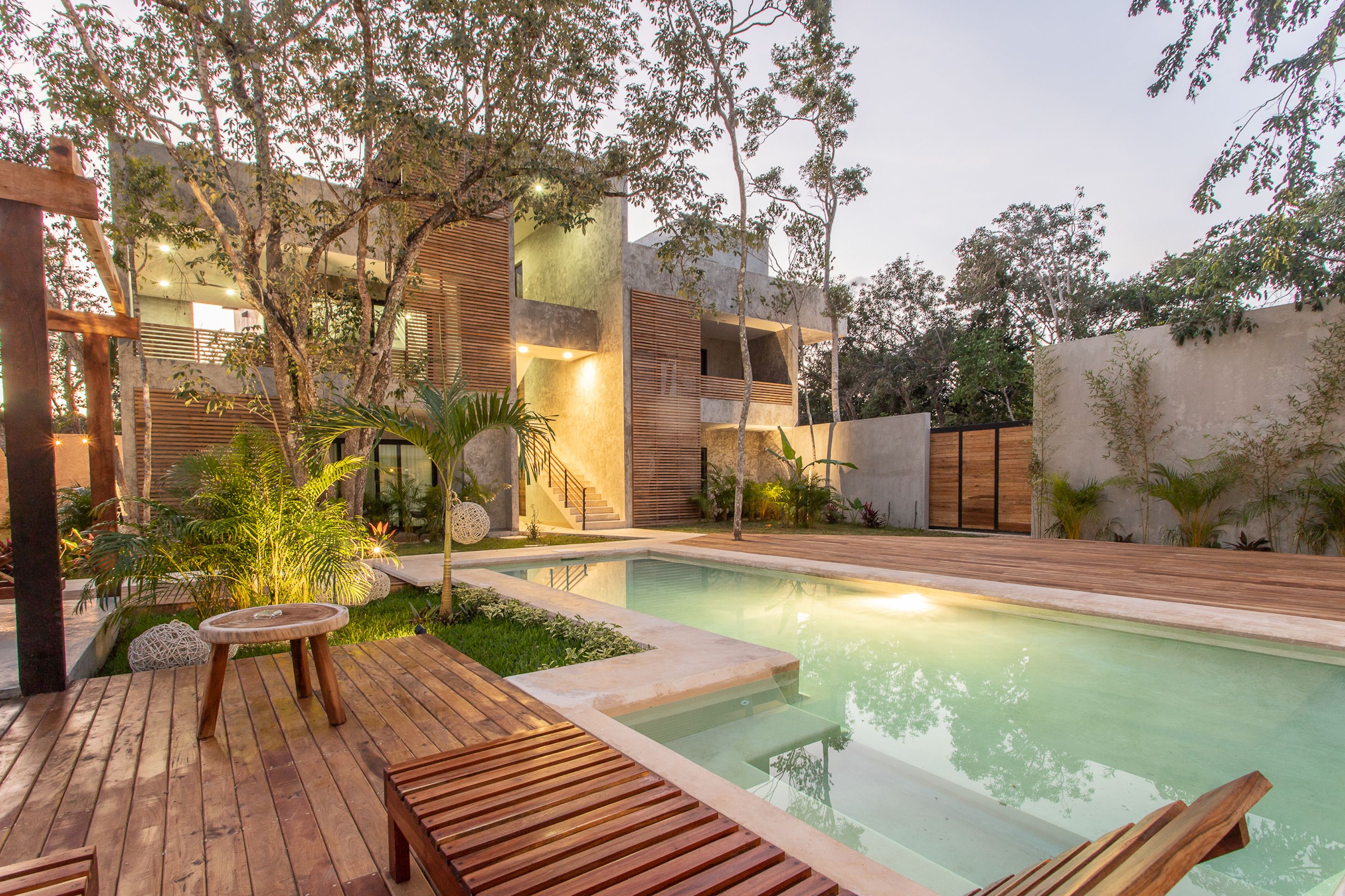Un espace piscine extérieur moderne, doté d’une terrasse en bois, d’une petite table ronde et d’un banc intégré.